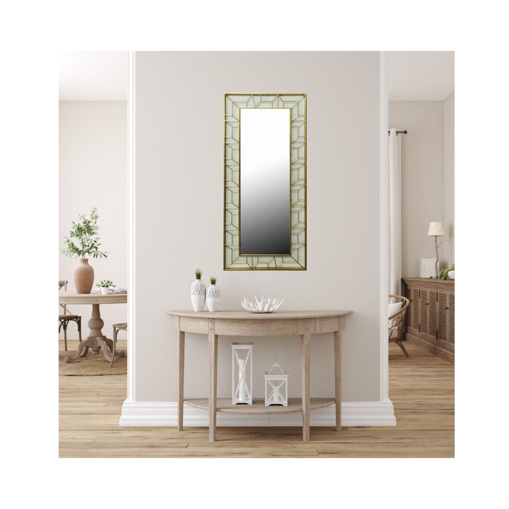 Ένας χρυσός μεταλλικός καθρέπτης με πλαίσιο με γεωμετρικά σχήματα σε ανοιχτόχρωμο μπεζ τοίχο