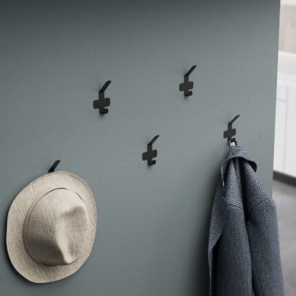 Μεταλλική μαύρη κρεμάστρα 1 θέσης τοποθετημένη σε γκρι τοίχο με κρεμασμένο ένα γκρι παλτό και ένα μπεζ καπέλο.