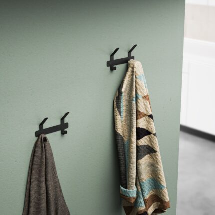 Μεταλλική μαύρη κρεμάστρα 2 θέσεων τοποθετημένη σε μπεζ τοίχο με κρεμασμένο ένα γκρι παλτό