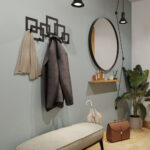 Μαύρη μεταλλική κρεμάστρα έξι θέσεων με σχέδιο κύβους τοποθετημένη σε τοίχο στο χωλ δίπλα από καθρέφτη