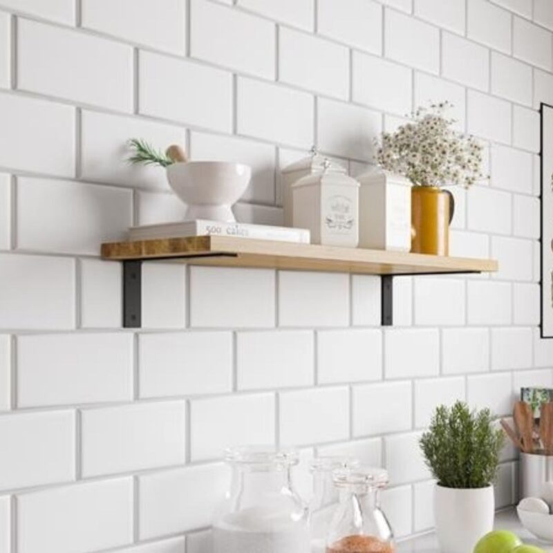 Ένα ξύλινο ράφι που στηρίζεται με μαύρες μεταλλικές γωνίες σε λευκό τοίχο