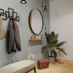 Ένα μεταλλικό πλαίσιο για καθρέφτη στρόγγυλο σε μαύρο χρώμα τοποθετημένο σε χολ με πράσινο τοίχο