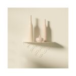 Ένα ράφι με κοπή λέιζερ σε τοίχο με κρεμ βάζα