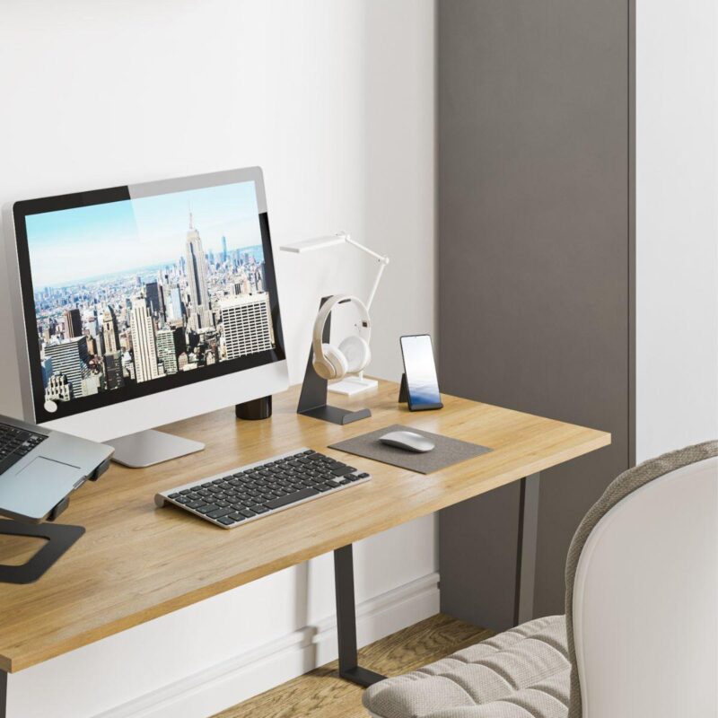 Ένα γραφείο εργασίας με μία οθόνη υπολογιστή, μία βάση για κινητό, ένα πληκτρολόγιο και μία μεταλλική βάση ακουστικών